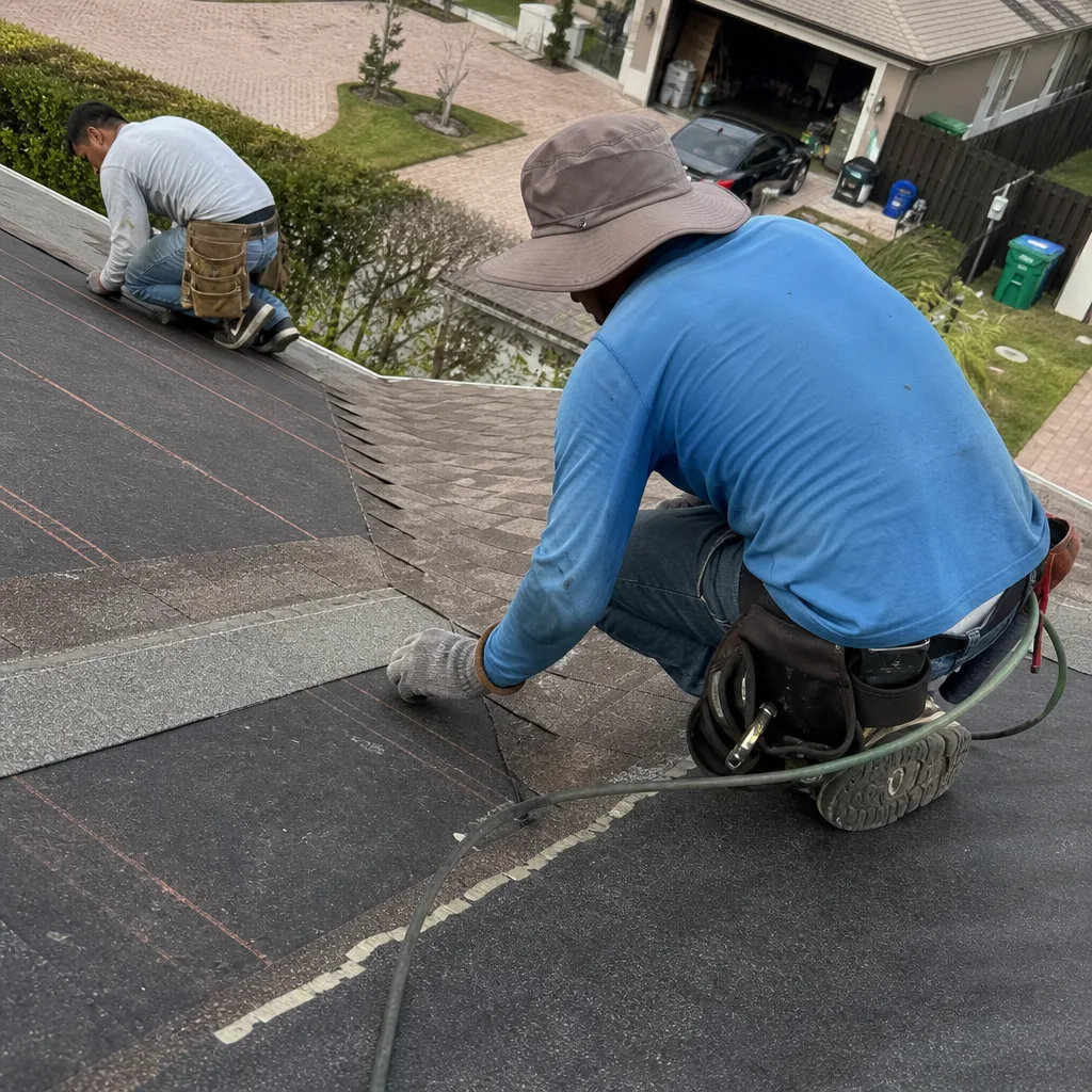 Two professional contractors installing asphalt shingles on a residential roof